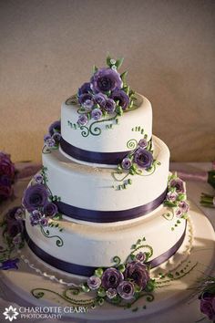 a three tiered cake with purple flowers on it