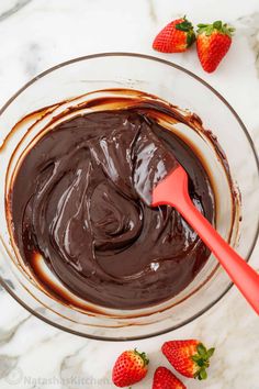 chocolate pudding in a glass bowl with strawberries on the side