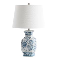 a blue and white vase lamp with a white shade on the top, sitting against a white background