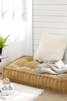 a bed that has some books on it and a plant in the corner next to it