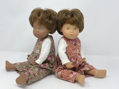 two dolls sitting next to each other on a white surface