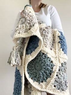 a woman is holding a crocheted blanket