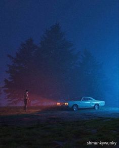 two people standing in the dark near a car