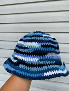 a person's hand wearing a crocheted blue and white hat on top of their head