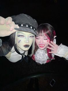 two people dressed in costumes posing for the camera at night with their faces painted white and black