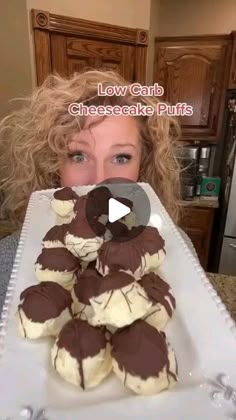 a woman holding up a plate with chocolate covered cookies on it and the words low carb cheesecake puffs in front of her face