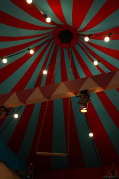 a large red and blue striped tent with lights on it's ceiling is lit up