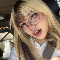 a woman with glasses and piercings sitting in a car