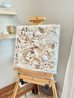 an easel with seashells on it in front of a white wall