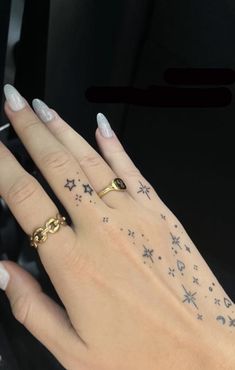 a woman's hand with stars and moon tattoos on it