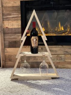 a bottle of wine and two glasses on a shelf in front of a fire place