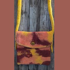 an orange and yellow handbag hanging on a wooden wall next to a brown fence