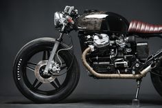 a black and brown motorcycle parked on top of a gray floor next to a wall