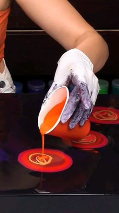 a person in white gloves pours orange liquid onto an object