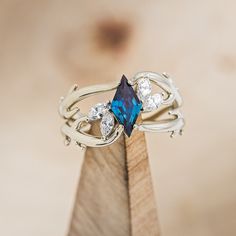 a blue ring with white diamonds on it sitting on top of a piece of wood