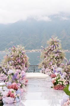 an outdoor ceremony setup with flowers on the aisle and mountains in the backgroud