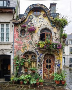 a house with flowers and plants on the outside, painted in multi - colored colors