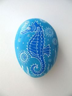 a painted rock sitting on top of a white table covered in blue and white designs