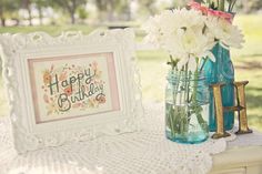 a vase with flowers and a happy birthday sign in front of it on a table