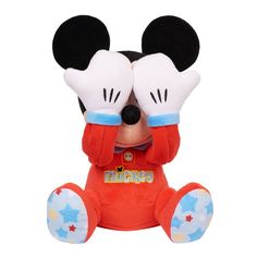 a mickey mouse stuffed animal sitting on top of a white surface with its eyes closed