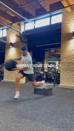 a man holding a basketball while standing next to a box in a gym with the words improve your stability written on it