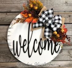 a welcome sign hanging on the side of a wooden wall with fall leaves and pumpkins