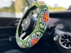 the steering wheel cover is decorated with colorful crochet and has flowers on it