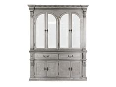 a white china cabinet with glass doors and carvings on the front, against a white background