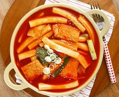 a bowl of soup with tofu, carrots and broth