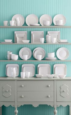 white dishes and cups are arranged on shelves in front of a blue wall with the words,