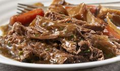 a white plate topped with meat and veggies next to a fork on top of a table