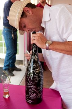 a man is smelling a wine bottle with writing on it