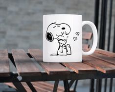 a white coffee mug sitting on top of a wooden table next to a brick wall