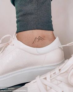 a woman's foot with a small mountain tattoo on her lower back side view