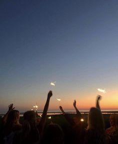 a group of people standing next to each other with their hands in the air holding sparklers