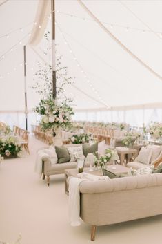 the inside of a tent with couches and tables set up for a wedding reception