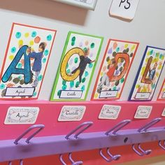 a row of magnets on a wall with letters and numbers attached to them, hanging from hooks