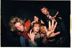 a group of young people standing around each other with their hands up in the air