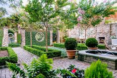 an outdoor garden area with potted plants and stone walls, surrounded by brick pavers