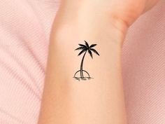 a woman's arm with a small palm tree tattoo on the left side of her wrist