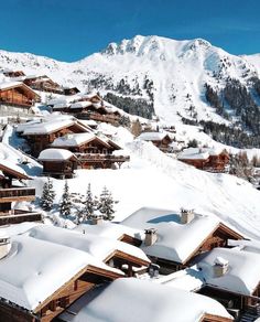 the snow covered mountains are in the distance with houses on each side and trees at the bottom