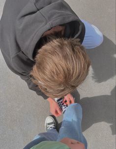 a young boy is looking down at his cell phone