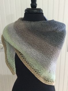 a knitted shawl on top of a mannequin headdress in grey and green