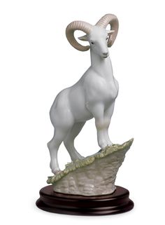 a statue of a ram standing on top of a rock in front of a white background