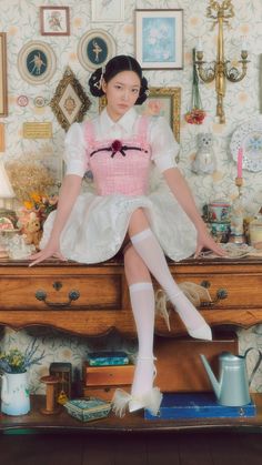 a woman sitting on top of a wooden dresser