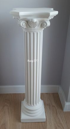 a white pedestal in the corner of a room