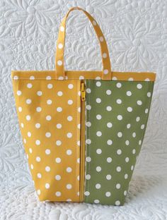 two bags sitting side by side on top of a white quilted bedding covered in green and yellow polka dot fabric