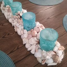 there are three blue candles on the table with shells and seashells around it