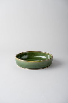 a green bowl sitting on top of a white table