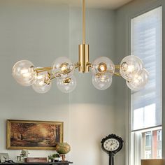 a chandelier hanging from a ceiling in a living room with a clock on the table